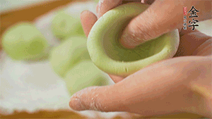 將均分的艾草面團搓成圓，挖一個窩，放入餡心，再搓成圓。