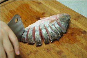 將鱸魚清洗干凈，從脊椎處切斷至腹部，腹部保留1cm左右不要切斷。