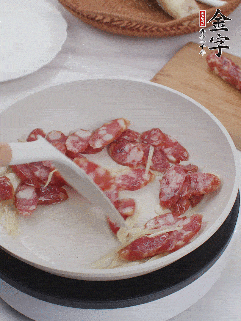 油溫3成熱時(shí)，下姜絲、蒜片、香腸炒出油脂。