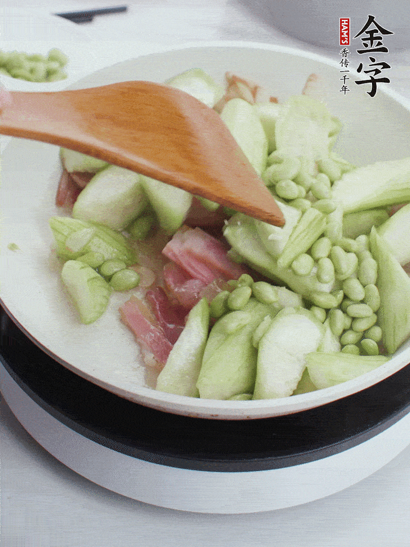 依次下絲瓜、青豆翻炒，炒至絲瓜打蔫縮小。
