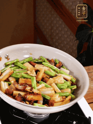 油熱下蒜末、干辣椒、醬肉煸炒出香味，依次下藕條、豆角翻炒均勻
